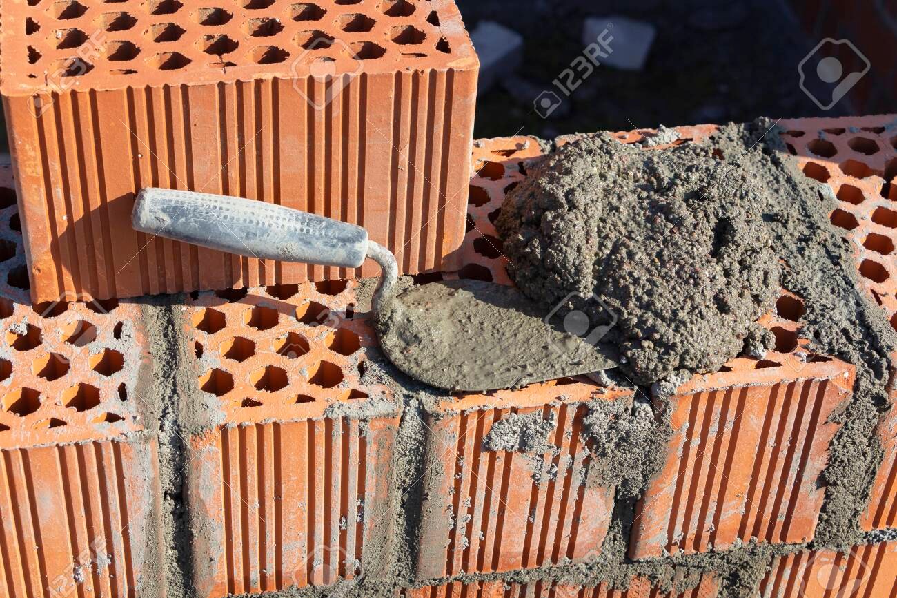 Spatula and cement mortar, red brick masonry, construction concept