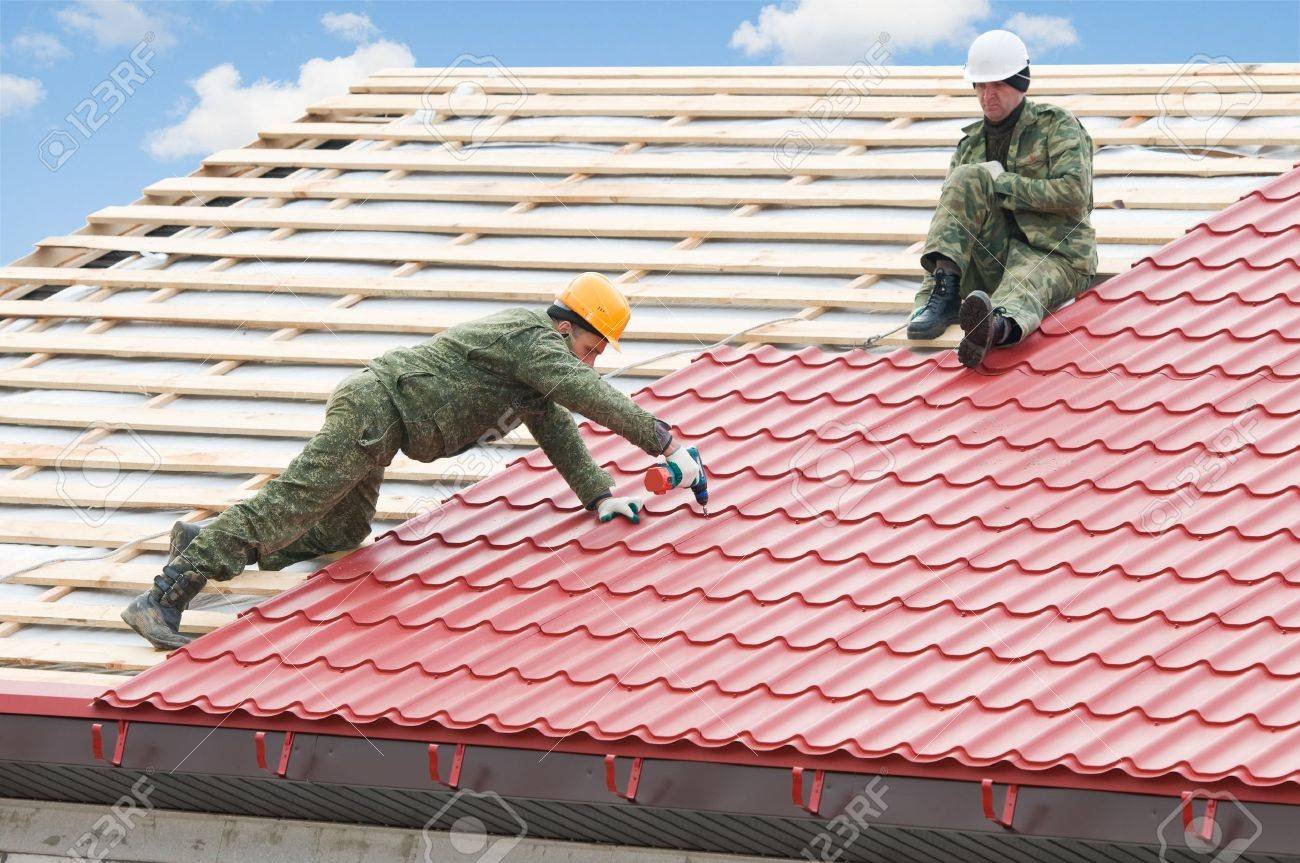 8396835-two-workers-on-roof-at-works-with-metal-tile-and-roofing-iron