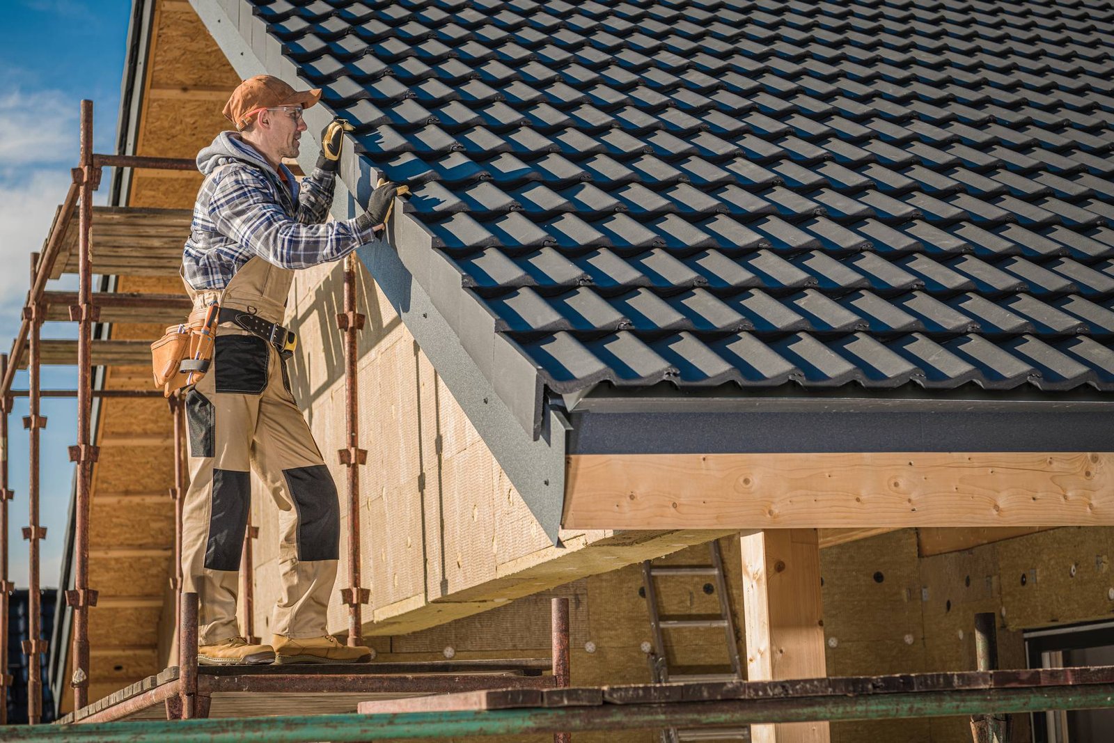 Professional Roofer Worker Finishing Ceramic Roof Tiles Installation. Smiling and Happy Worker on a Scaffolding.