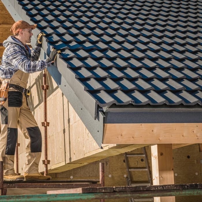 Professional Roofer Worker Finishing Ceramic Roof Tiles Installation. Smiling and Happy Worker on a Scaffolding.